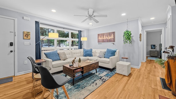 A modern living room with a white sofa, a wooden coffee table, and a blue rug. - Charming Downtown Corner Cottage - 1 Block Walk to Food & Fun - Dog Friendly! (Southern Pines)