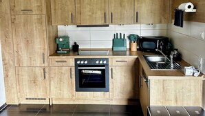 A modern kitchen with wooden cabinets, a built-in oven, a microwave, and a sink. - Alpine Soul (Feldberg) - Terrace (Feldberg (Schwarzwald))
