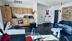 A modern living space with a kitchen, dining area, and a cozy seating area with a stone accent wall. - Alpine Soul (Feldberg) - Terrace (Feldberg (Schwarzwald))