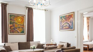 Un salon comprenant un canapé, une table basse, un lustre et deux tableaux accrochés au mur.