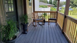 A wooden deck with two rocking chairs and potted plants. - 2 BM/French Country Style DPLX (Davenport)