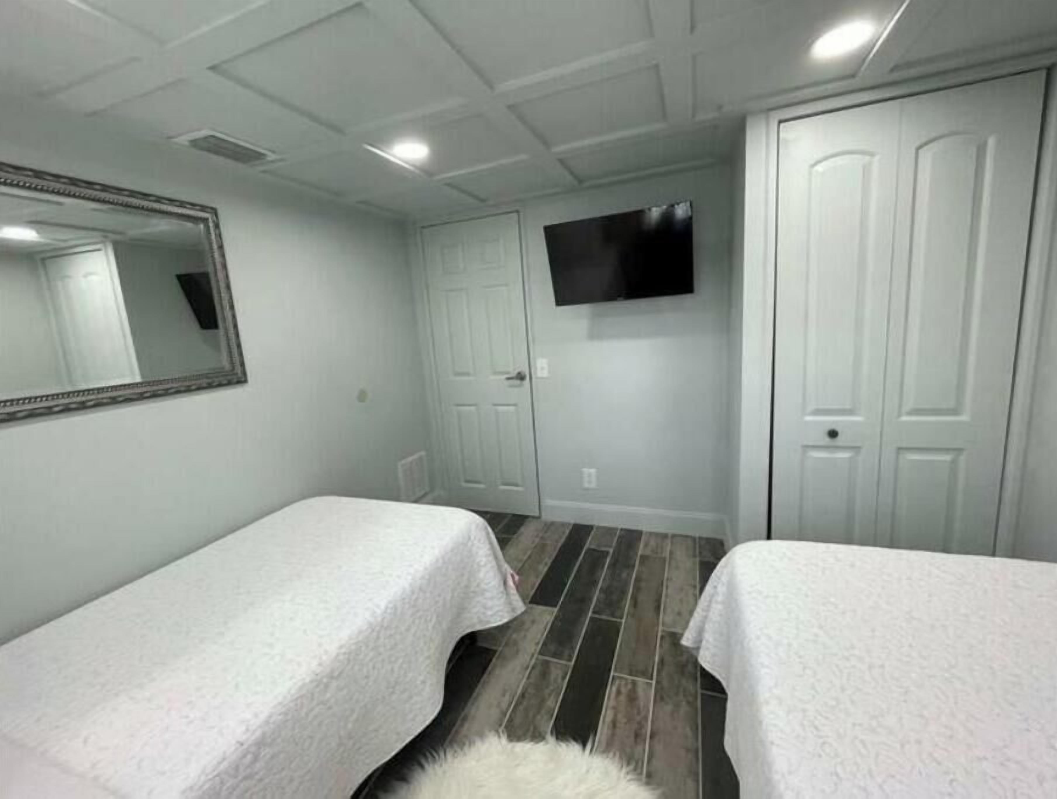 A bedroom with two beds, a TV mounted on the wall, and a mirror.