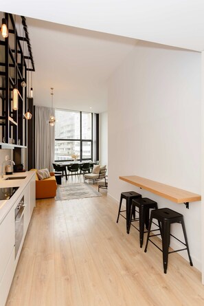 Une cuisine moderne avec un coin repas, un plancher en bois et une grande fenêtre donnant sur la ville.