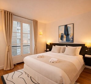 A neatly made bed with white linens, a headboard, and two bedside lamps. - CORNEILLE (Paris)