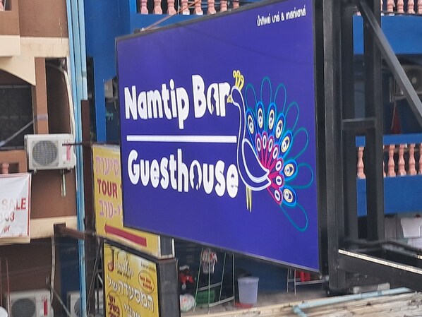 A sign for Namtip Bar Guesthouse with a peacock design.