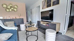 A modern living room with a sofa, coffee table, ottoman, and a TV on a wooden cabinet.