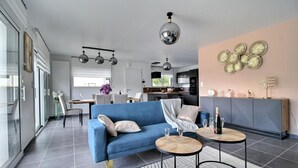 A modern living room with a blue sofa, two round coffee tables, and a kitchen in the background.