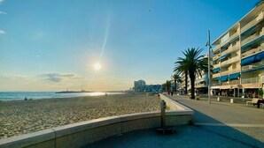 A beachside promenade with a sandy beach, a clear sky, and buildings in the background. - Air-conditioned villa with swimming pool between the sea and the Cevennes mountains. (La Calmette)