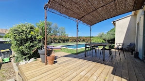 A wooden deck with a pool, outdoor furniture, and a pergola providing shade. - Air-conditioned villa with swimming pool between the sea and the Cevennes mountains. (La Calmette)