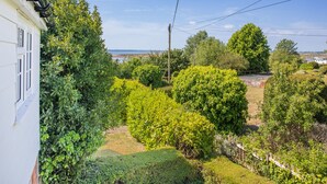 A residential area with a white building, lush green gardens, and a view of the sea. - Welcome to this delightful fisherman’s cottage on the unique Island of Mersea. (Mersea Island)