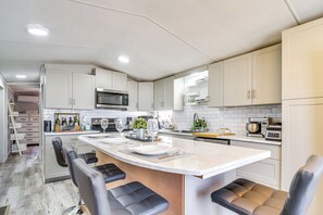 Een moderne keuken met een groot eiland, witte kasten en roestvrijstalen apparatuur.