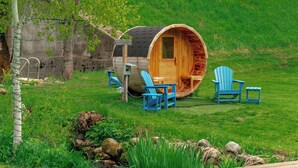 A wooden barrel structure with a window, two blue Adirondack chairs, and a small table. - Large tent on massive Big Rock Creek Estate! (Saint Croix Falls)