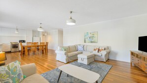 A modern living room with a sofa, a coffee table, and a dining area with chairs and a table.