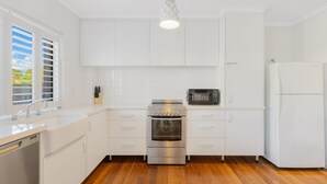 A modern kitchen with white cabinets, a stainless steel oven, a microwave, and a dishwasher.