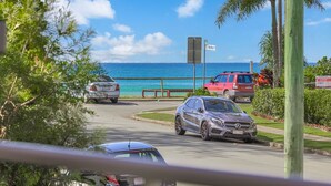 A coastal road with parked cars, a bench, and a sign for Graham Street.