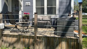 Une maison à l’extérieur gris, avec une terrasse en bois et le numéro « 310 » peint sur le mur.