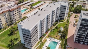 Un hôtel de grande hauteur, avec de nombreux étages, une piscine centrale et de nombreux espaces verts environnants.