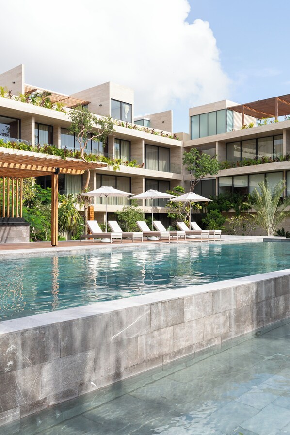 A modern hotel with a swimming pool, sun loungers, and umbrellas. - Luxury 2Bed MT D104 By Sandy Powerful (Tulum)