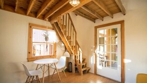 Ein Zimmer mit Holzboden, einer Treppe, einem Esstisch mit Stühlen und einer Tür mit Glasverkleidung.