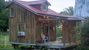 Eine rustikale Holzhütte mit einem Metalldach, einer Veranda und einem kleinen angebauten Schuppen.