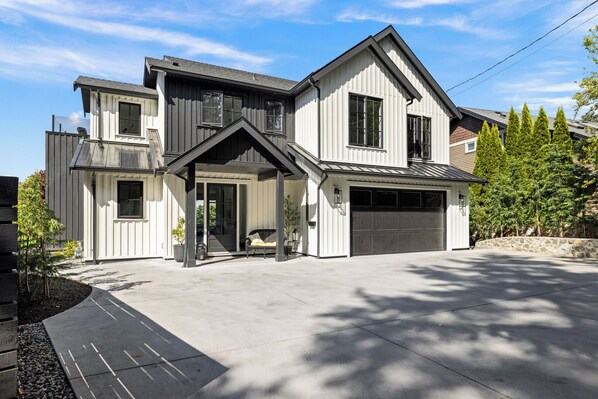 Ein modernes, zweistöckiges Haus mit Garage, überdachter Veranda und Auffahrt.