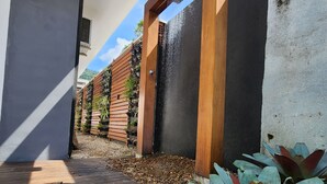 A modern outdoor area with a wooden deck, a black wall with vertical wooden slats, and a concrete pillar. - Rei dos Mares Suítes by Easy Hotéis (Ubatuba)