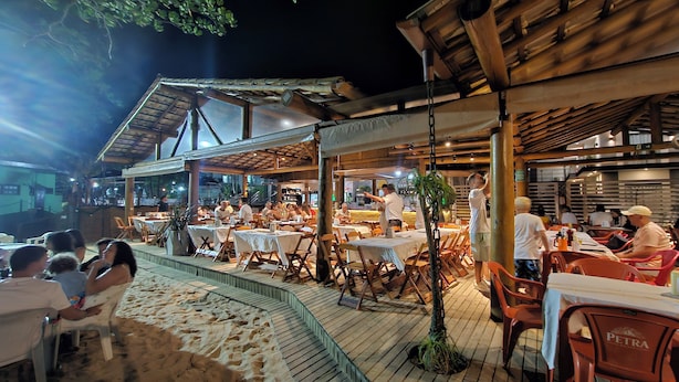 An outdoor dining area with tables and chairs, a covered seating area, and a view of the surrounding landscape. - Rei dos Mares Suítes by Easy Hotéis (Ubatuba)