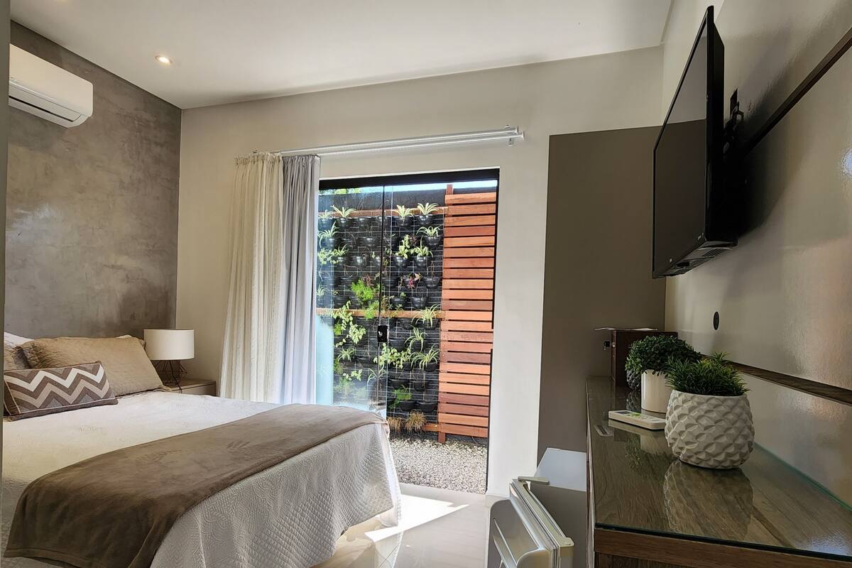 A modern bedroom with a bed, bedside table, and a TV mounted on the wall.