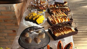 A buffet table with various food items including fruits, bread, and desserts. - Rei dos Mares Suítes by Easy Hotéis (Ubatuba)