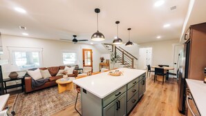 A modern kitchen with a central island, wooden flooring, and pendant lighting. - Little River Retreat (Townsend)