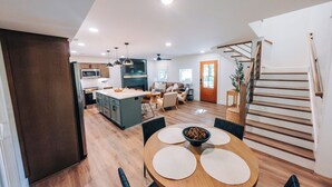 A modern kitchen with a central island, wooden flooring, and a dining area with a round table and chairs. - Little River Retreat (Townsend)
