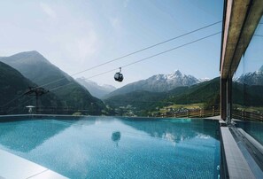 A clear view of a swimming pool with a cable car in the background and mountains.