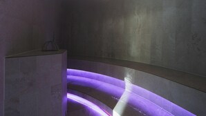 Une salle de bain moderne avec un lavabo aux lignes courbes et un éclairage violet.