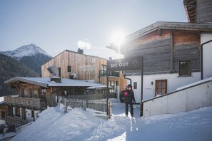 A ski resort with wooden buildings, a ski out sign, and a person in winter gear. - Grünwald Resort Sölden (Soelden)