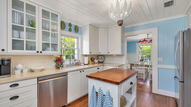 A kitchen with white cabinets, a wooden countertop, a dishwasher, and a refrigerator.