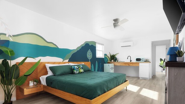 Ein modernes Schlafzimmer mit einem Holzbett, einem Schreibtisch und einer Küchenzeile.