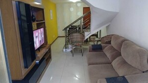 Ein Wohnzimmer mit Fernseher, einer Couch und einer Treppe.
