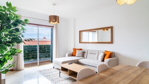 A modern living room with a sofa, a dining table, and a large window.