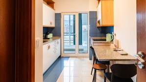 A modern kitchen with a dining area, featuring a sliding glass door leading to a balcony.