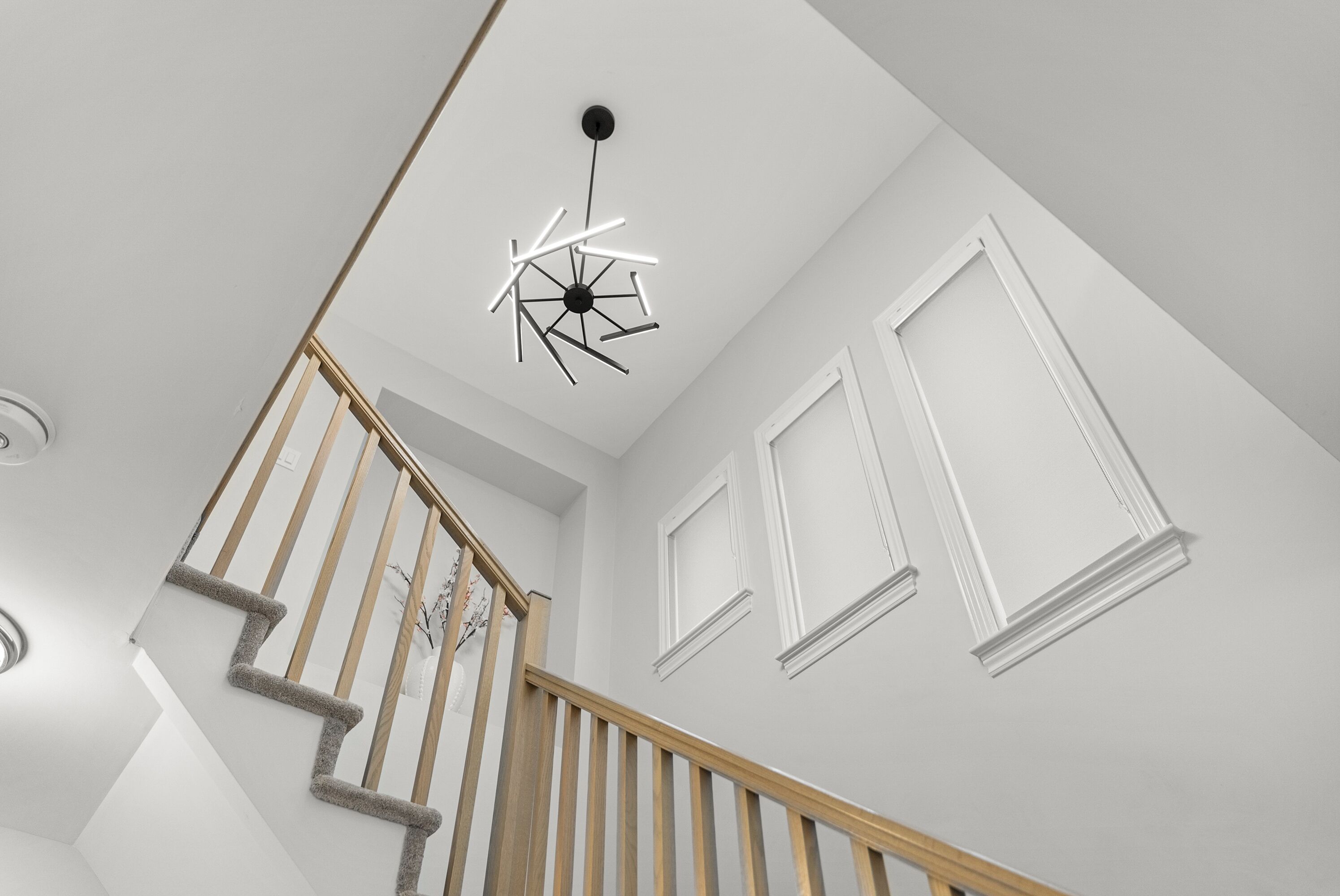 Un escalier avec des rampes en bois et un luminaire moderne au plafond.