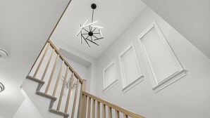 Una scala con ringhiere in legno e una moderna lampada a soffitto.
