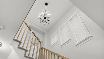 Un escalier avec des rampes en bois et un luminaire moderne au plafond.