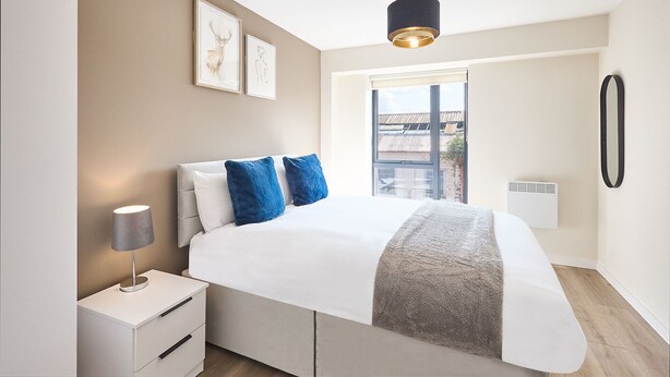 A modern bedroom with a bed, bedside table, lamp, and artwork on the wall. - GG-Guest House (Liverpool)