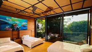A modern bedroom with three beds, a large painting, and a sliding glass door to a balcony.