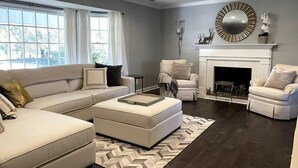 A modern living room with a sectional sofa, a fireplace, and a large mirror.