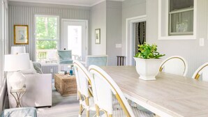 A dining area with a wooden table, white chairs, and a potted plant.