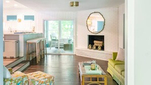 A spacious living area with a fireplace, a dining area with bar stools, and a kitchen with a refrigerator.