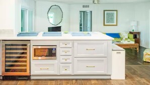 A modern kitchen with white cabinetry, a built-in oven, and a large island with a microwave.