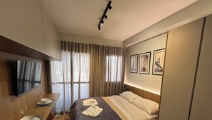 A hotel room with a bed, bedside table, TV, and curtains. - Brooklin subway - US Consulate - Vibra São Paulo (Jardim das Acacias São Paulo)
