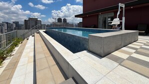 A rooftop pool with a city view, a red building, and a glass railing. - Brooklin subway - US Consulate - Vibra São Paulo (Jardim das Acacias São Paulo)